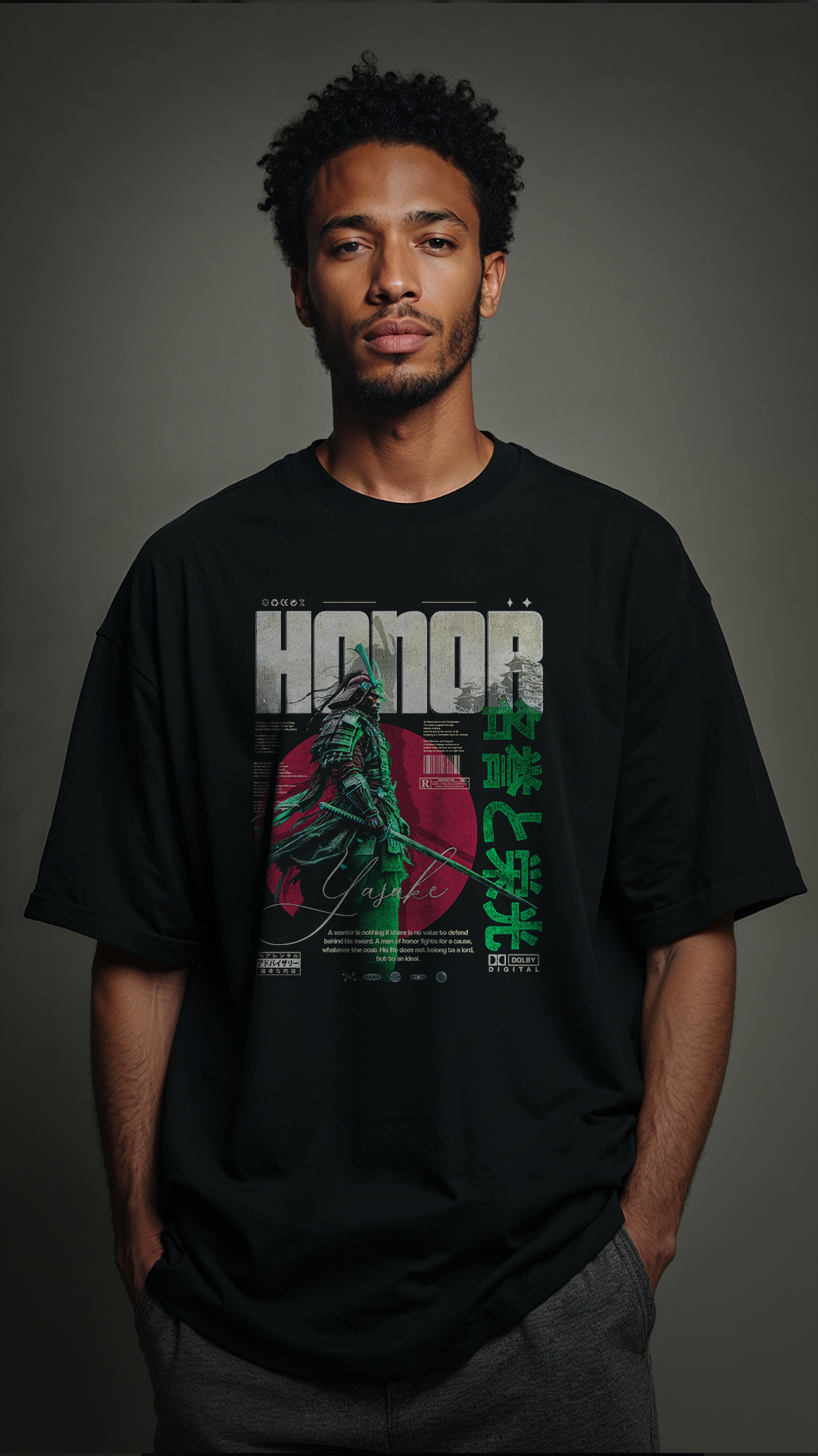 Jeune homme portant le t-shirt noir oversize HONOR Green vue face corps entier, graphic Yasuke samouraï vert et rouge bien visible sur la poitrine, coupe streetwear oversize, fond gris neutre
