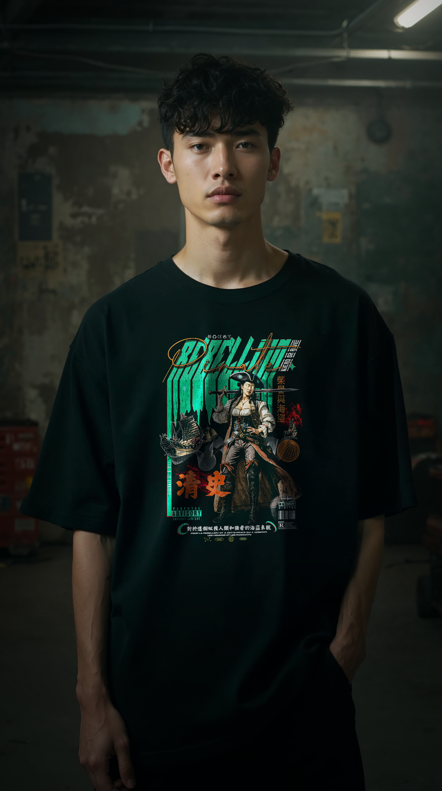 Jeune homme portant le t-shirt oversize noir REBELLION GREEN, coupe ample streetwear, design graphique rebelle, fond parking urbain industriel