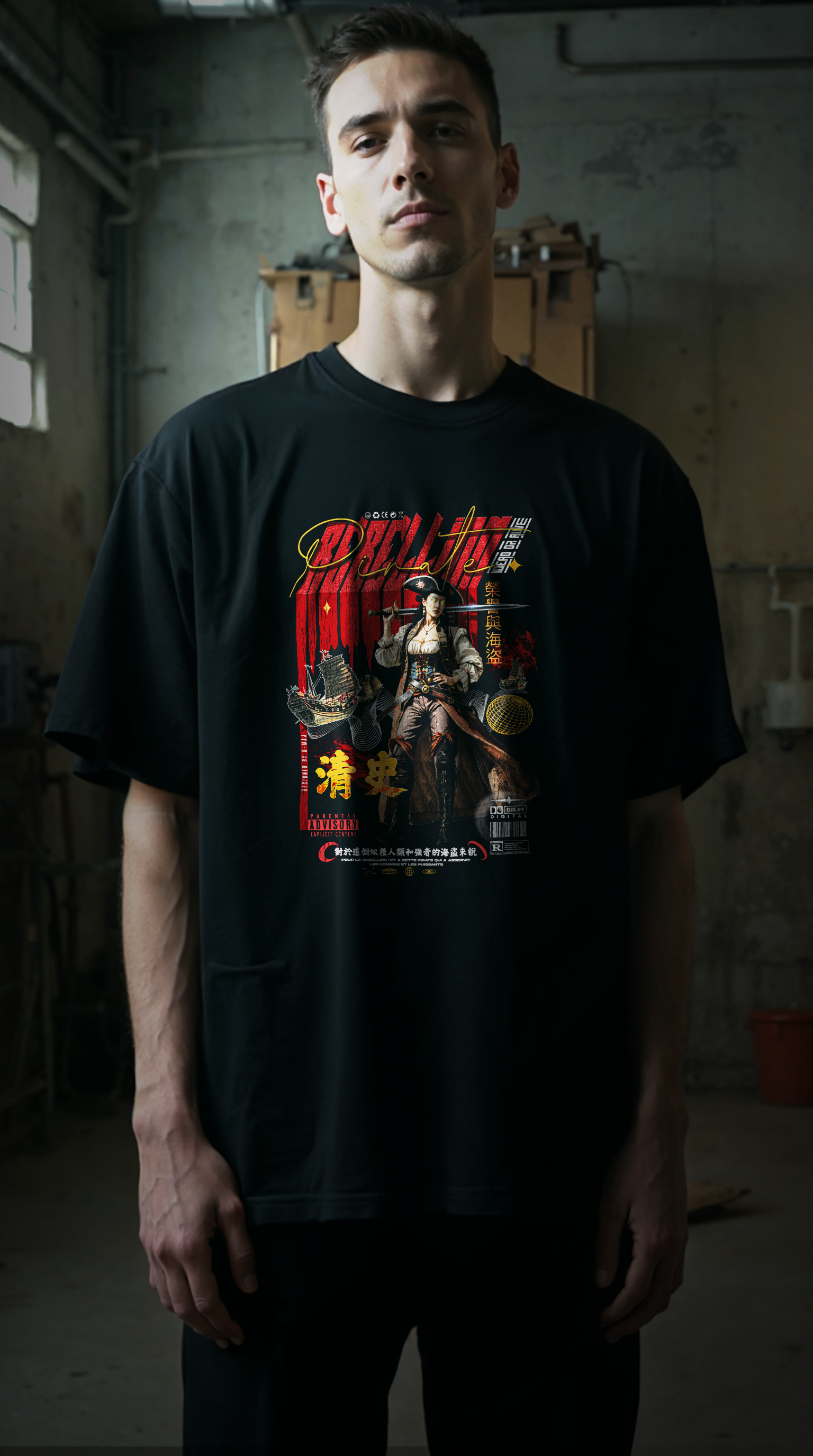 Jeune homme portant le t-shirt oversize noir REBELLION RED, coupe ample streetwear, design graphique rebelle, fond  urbain industriel