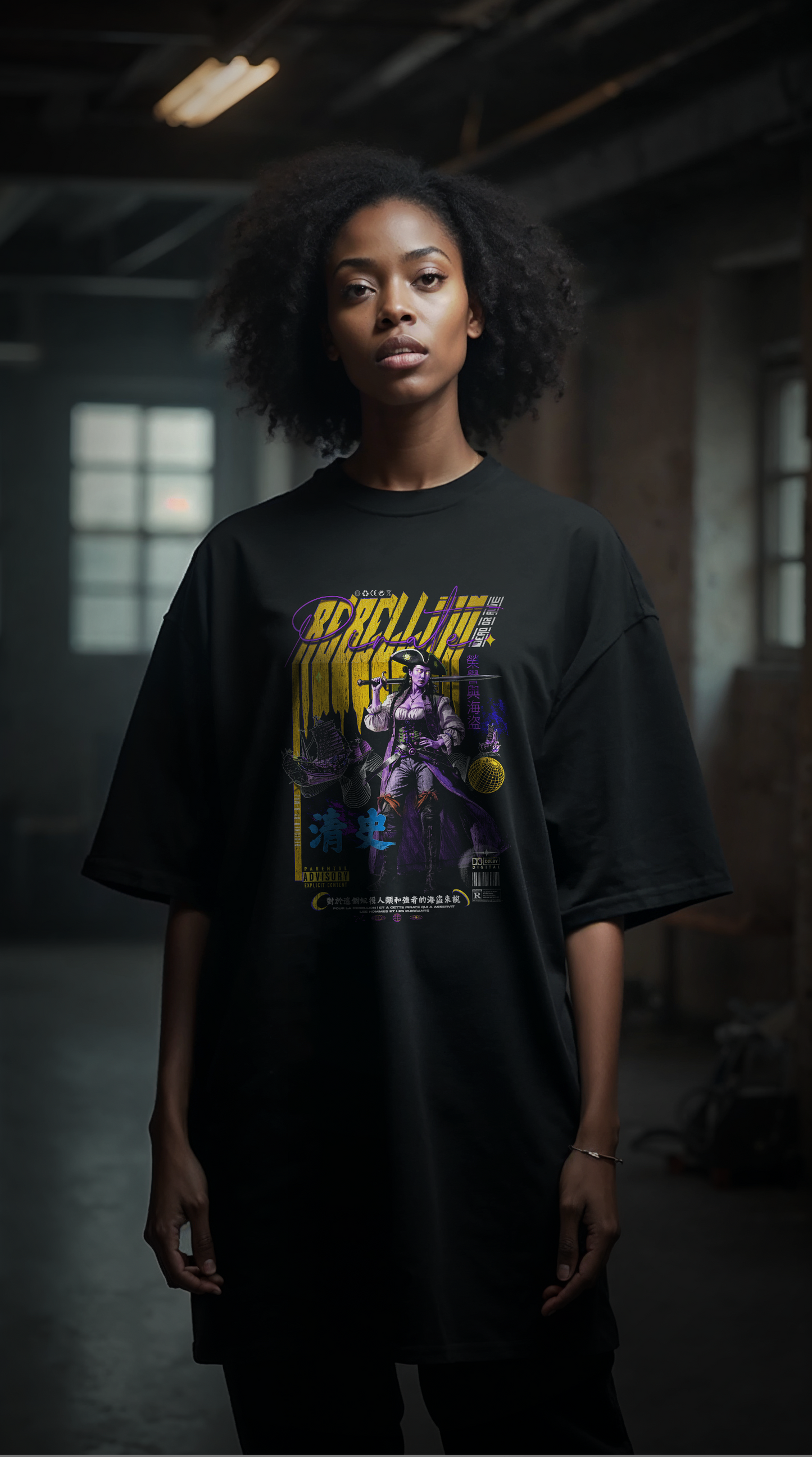 Femme blonde tatouée portant le t-shirt oversize noir REBELLION yellow and purple, style streetwear rebelle et féministe, coupe ample coton biologique
