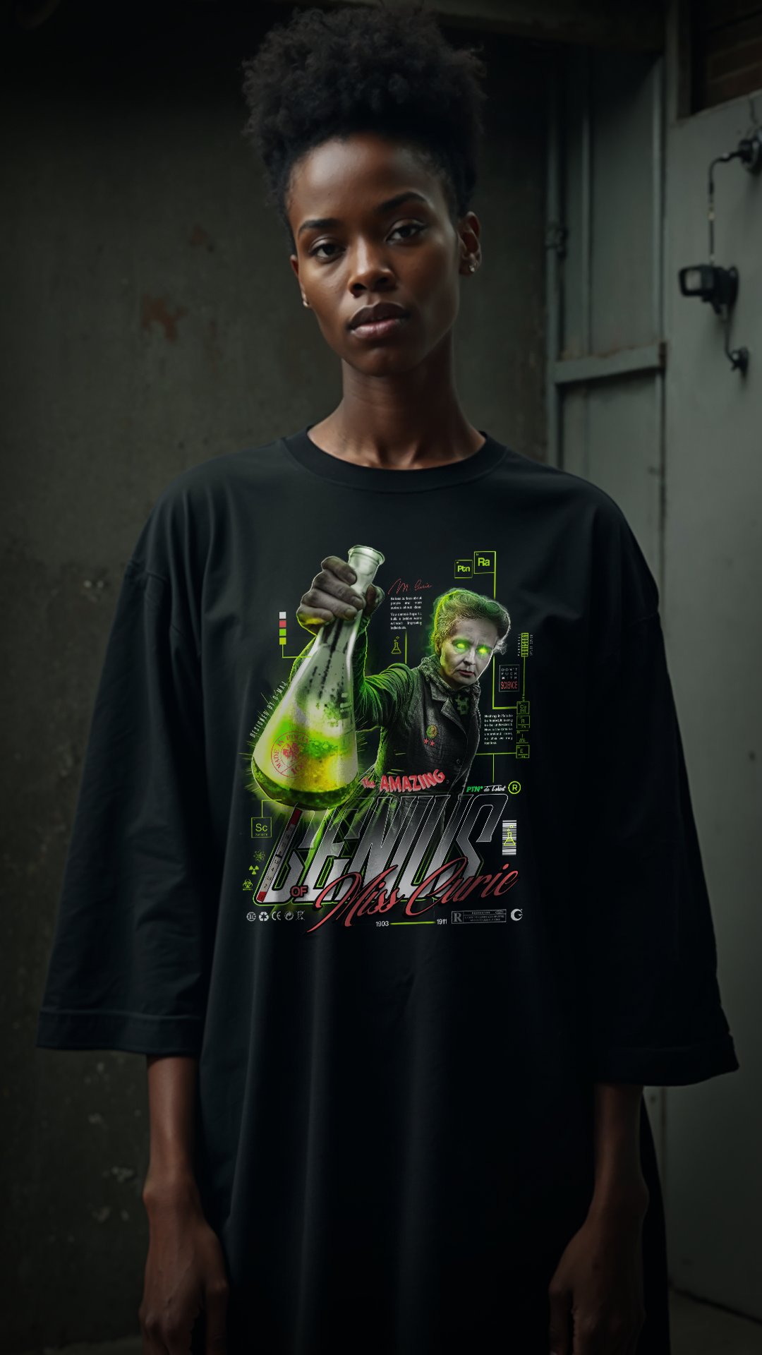Femme portant le t-shirt noir oversize GENIUS PTN* DE T-SHIRT comme une robe, graphic Marie Curie au flacon vert visible sur la poitrine, look streetwear unisexe, fond industriel sombre