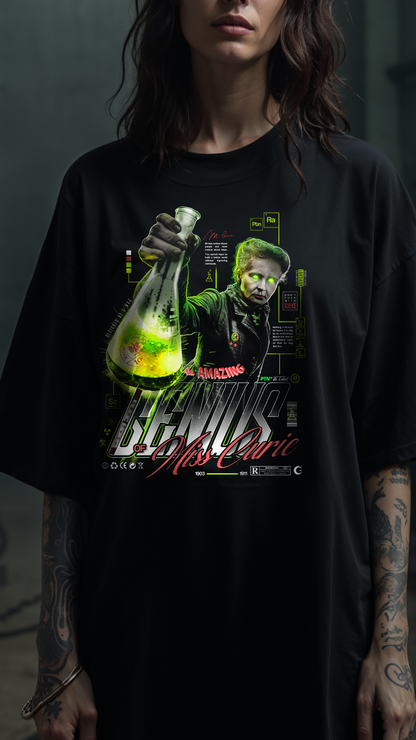 Vue rapprochée du graphic GENIUS PTN* DE T-SHIRT sur t-shirt noir oversize, design Marie Curie tenant un flacon vert lumineux bien visible, porté par une personne aux bras tatoués